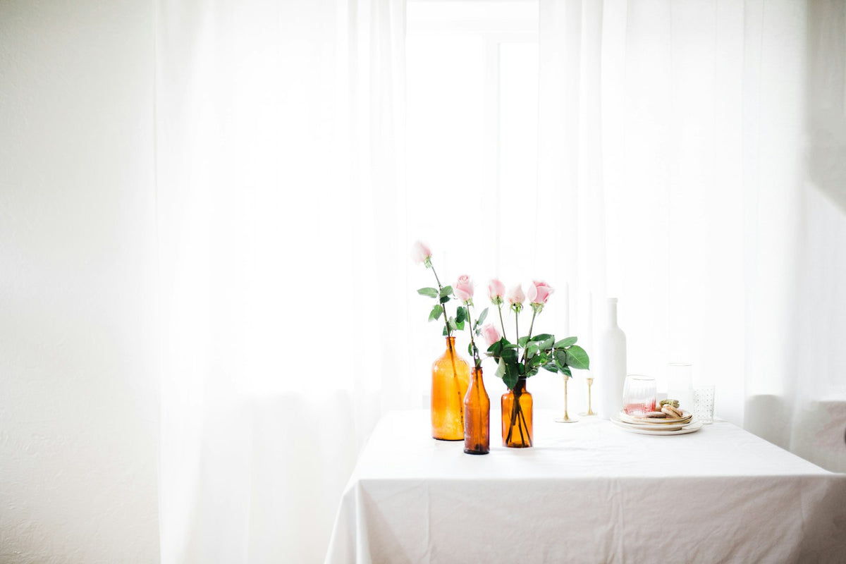 Amber glass bottles and pink roses by a soft-lit window